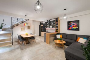 A modern living space with a dining area, kitchen, and a staircase.
