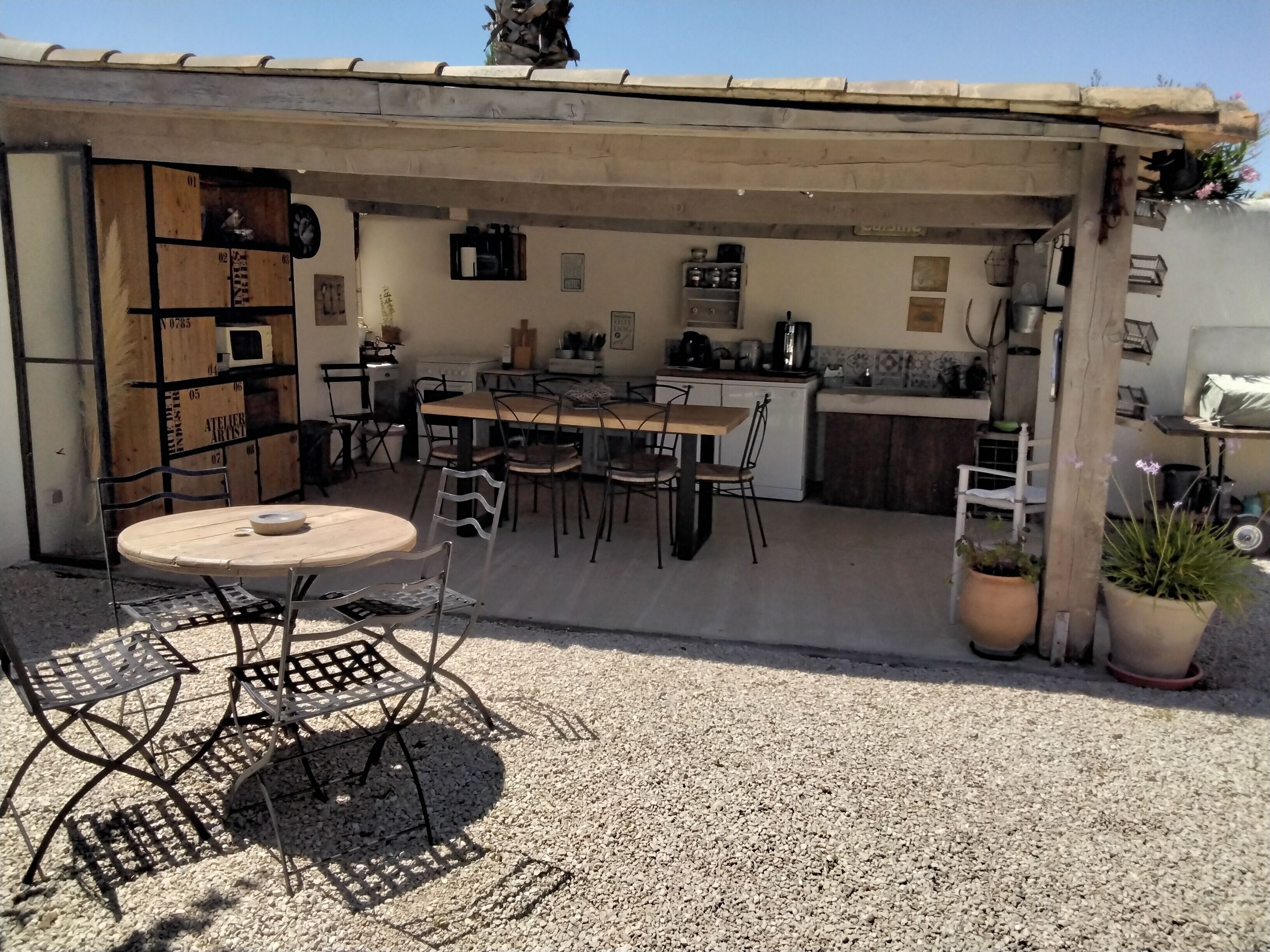 A compact outdoor kitchen area with a dining table and chairs, surrounded by potted plants.