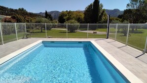 A rectangular swimming pool with clear blue water, surrounded by a white fence and a paved deck. - QUIET, COMFORTABLE PROVENCAL FARMHOUSE IN THE COUNTRYSIDE WITH SECURE SWIMMING POOL (Cheval-Blanc)