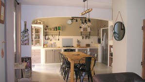 A modern kitchen with a dining area, featuring a wooden table, chairs, and a refrigerator. - QUIET, COMFORTABLE PROVENCAL FARMHOUSE IN THE COUNTRYSIDE WITH SECURE SWIMMING POOL (Cheval-Blanc)