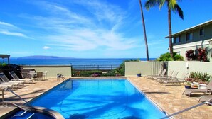 Uma piscina com espreguiçadeiras e vista para o mar.