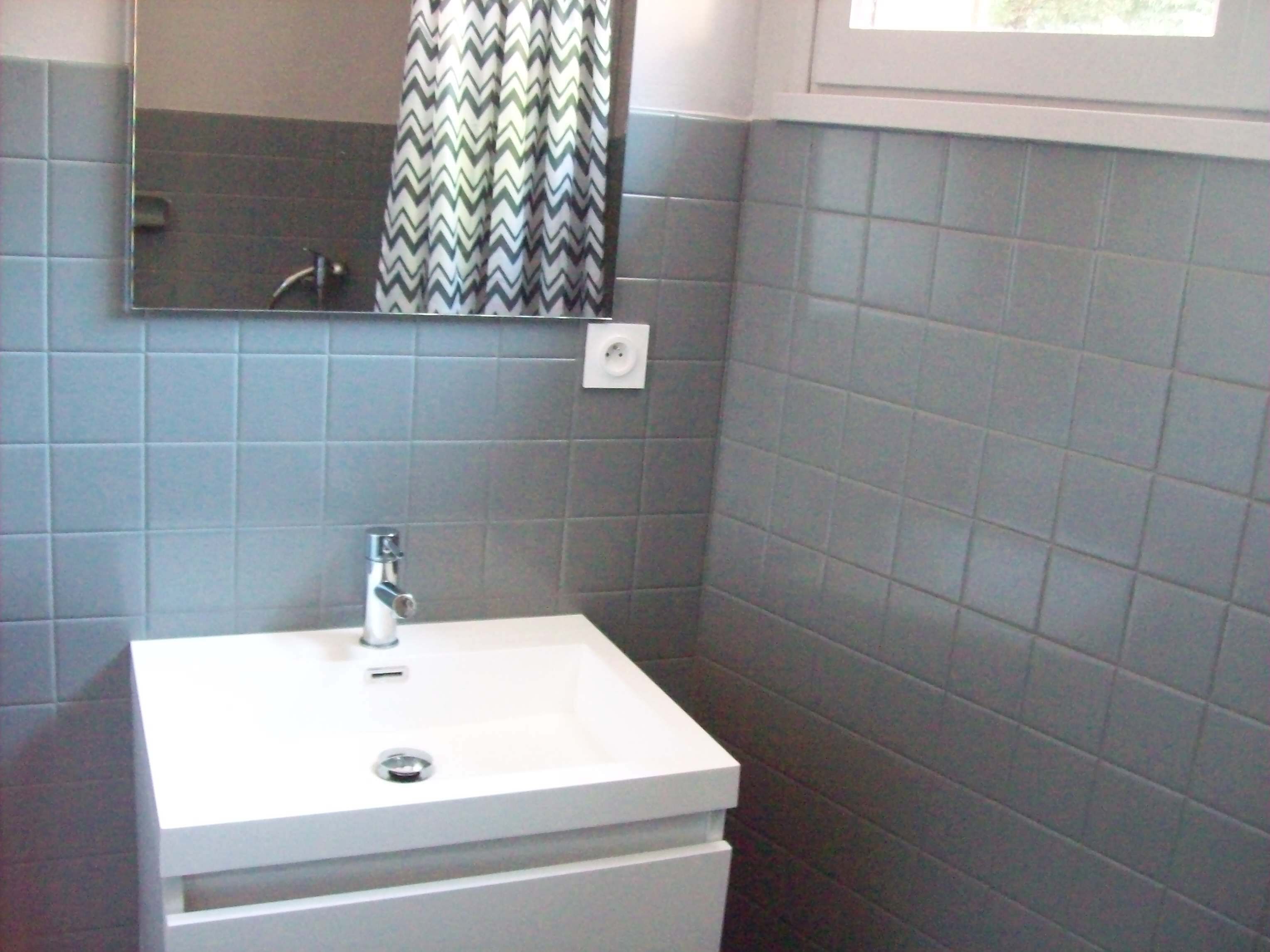 A bathroom with a white sink, a mirror above it, and a chevron-patterned shower curtain.