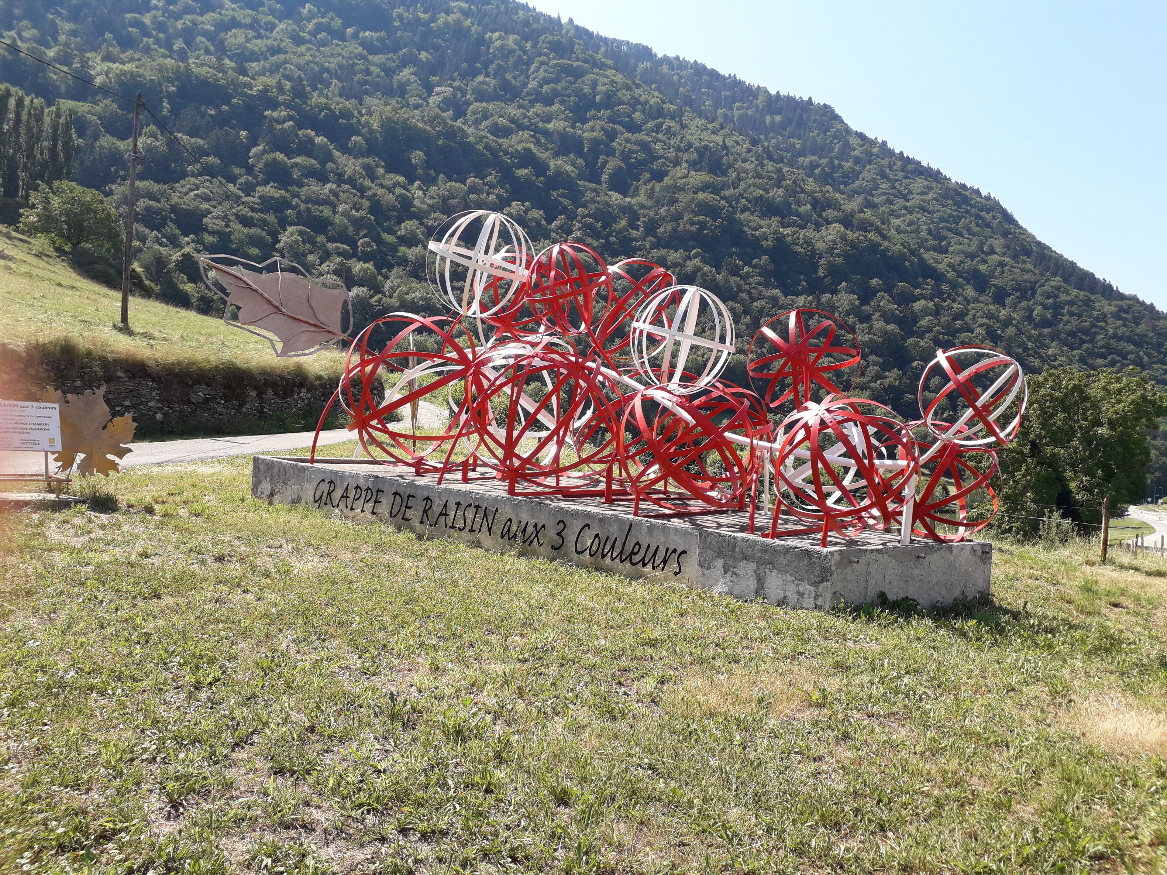Un jardín de esculturas con obras abstractas rojas y blancas, un letrero que dice 