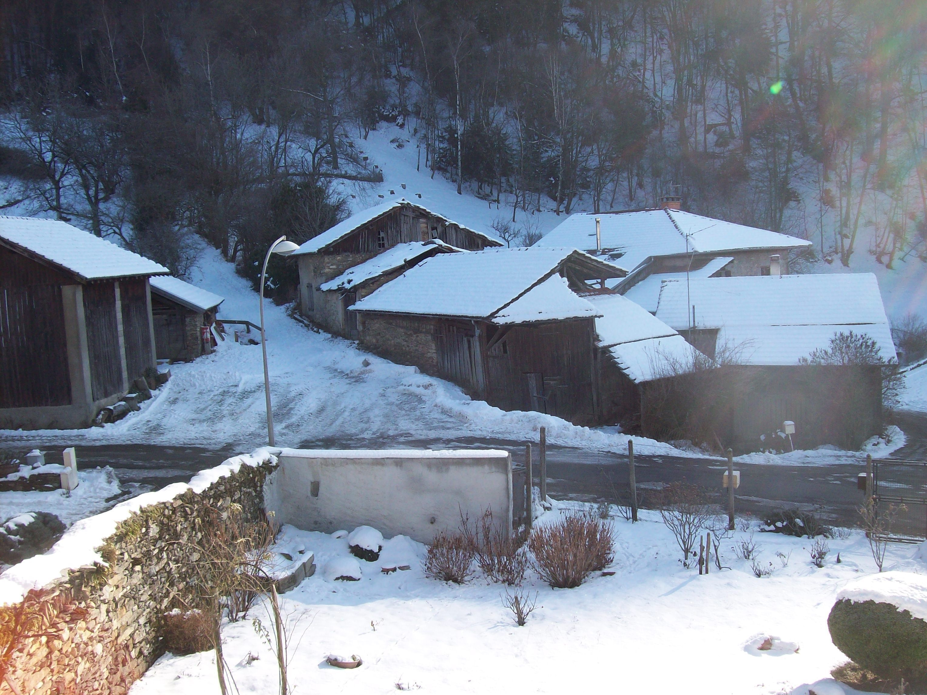 A rural village with snow-covered houses and a stone wall.