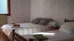 A neatly made bed with striped bedding and pillows, a wooden headboard, and a window with blinds.
