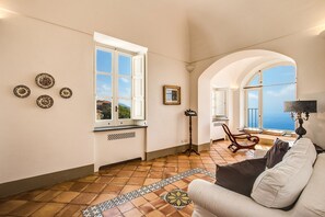 Une pièce spacieuse avec une grande fenêtre, un canapé, une table et un tapis décoratif.