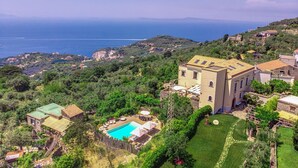 Una villa con piscina, rodeada de exuberante vegetación y vistas a la costa.