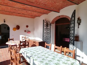 Un comedor con techo de ladrillo, sillas de madera y mesas cubiertas con manteles florales.