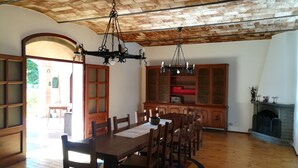 Ein Essbereich mit Holztisch und Stühlen, einer Kandelaber und einer Ziegeldecke.