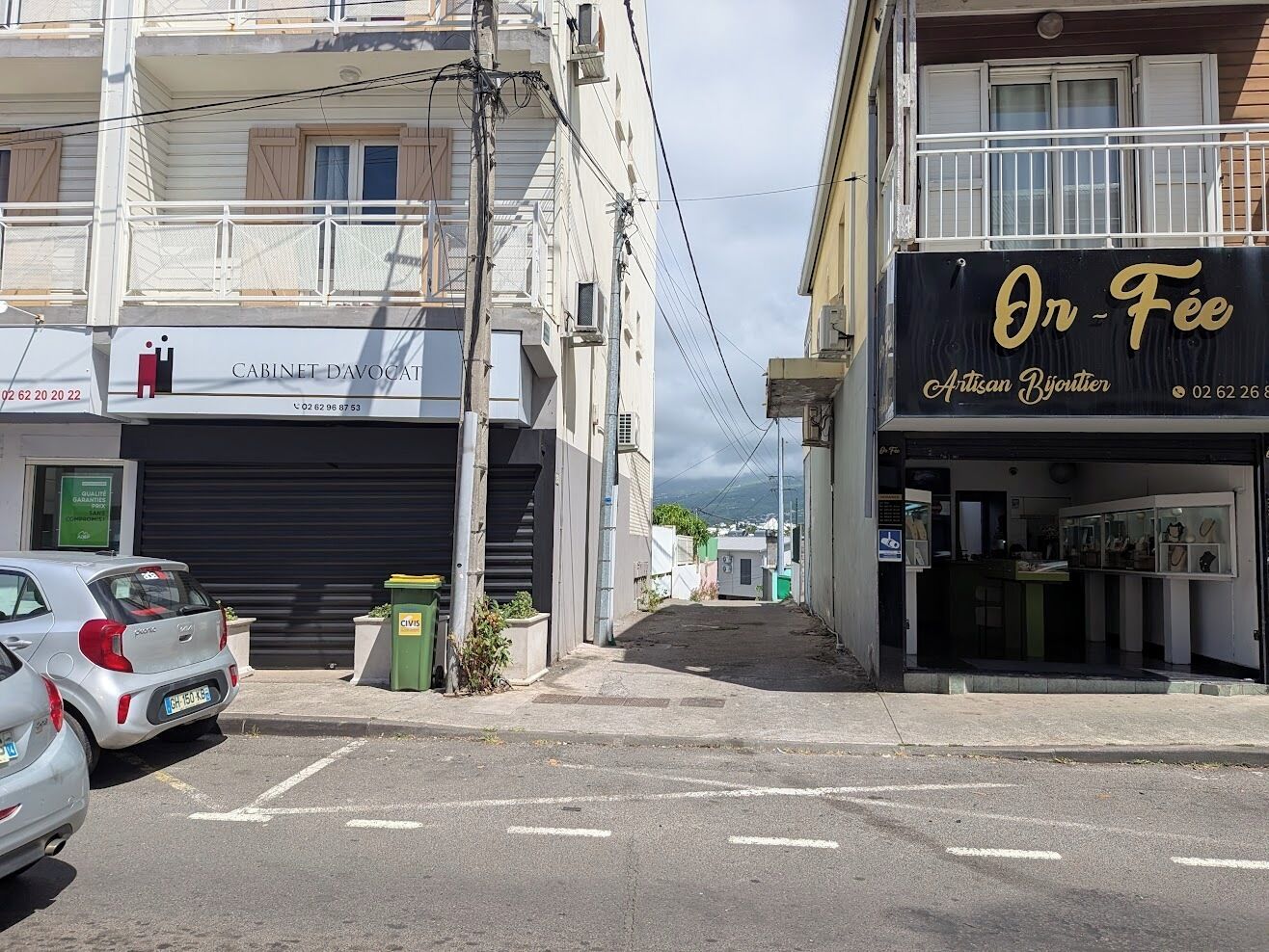 Une vue de rue avec un bâtiment sur la droite, portant l’inscription « On Fee Artisan Bijouter ».