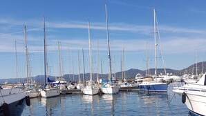 Un port de plaisance où sont amarrés de nombreux voiliers, sur des eaux calmes, le tout étant entouré de collines en arrière-plan.