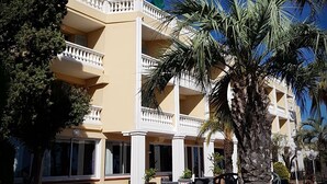 Un hôtel à plusieurs étages doté de balcons, d’un espace extérieur aménagé et de palmiers.