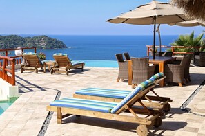 A poolside area with lounge chairs, a table, and an umbrella.