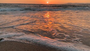 Ein Strand bei Sonnenuntergang, sanfte Wellen erreichen das Ufer.