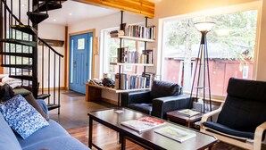 Uma sala de estar moderna com escada, estante, sofá e mesa de centro.