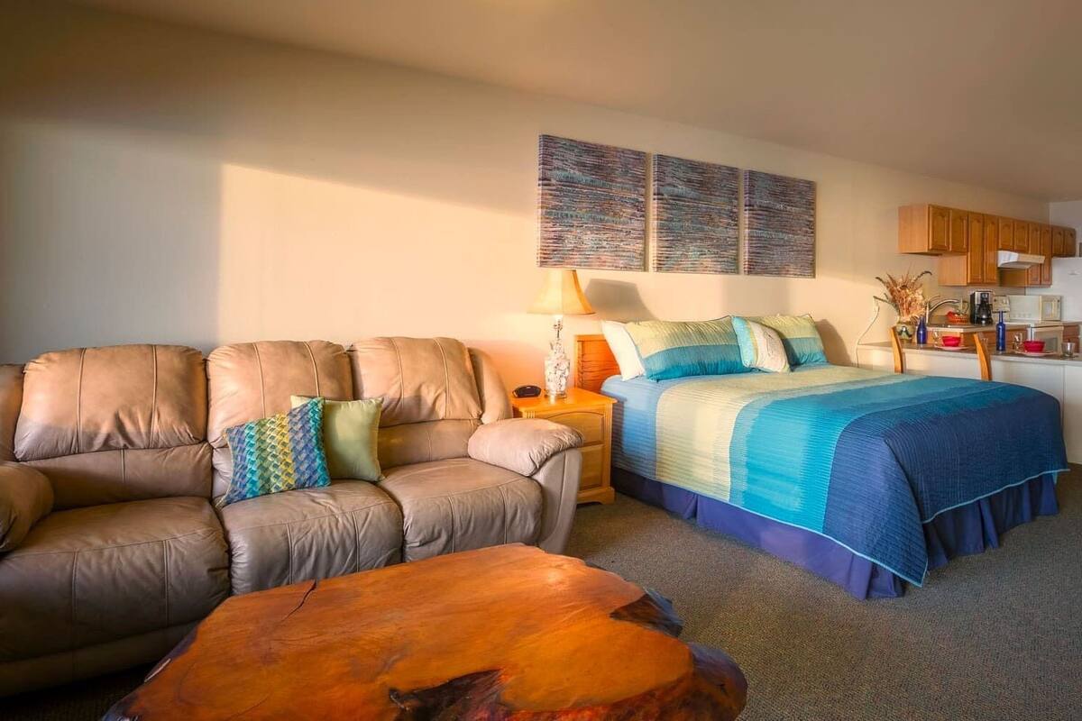 Ein Schlafzimmer mit einem Bett, einem Schlafsofa, einem Nachttisch und einem kleinen Holztisch.