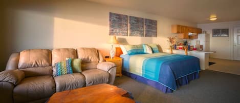 Un dormitorio con cama, sofá, mesita de noche y una pequeña mesa de madera.