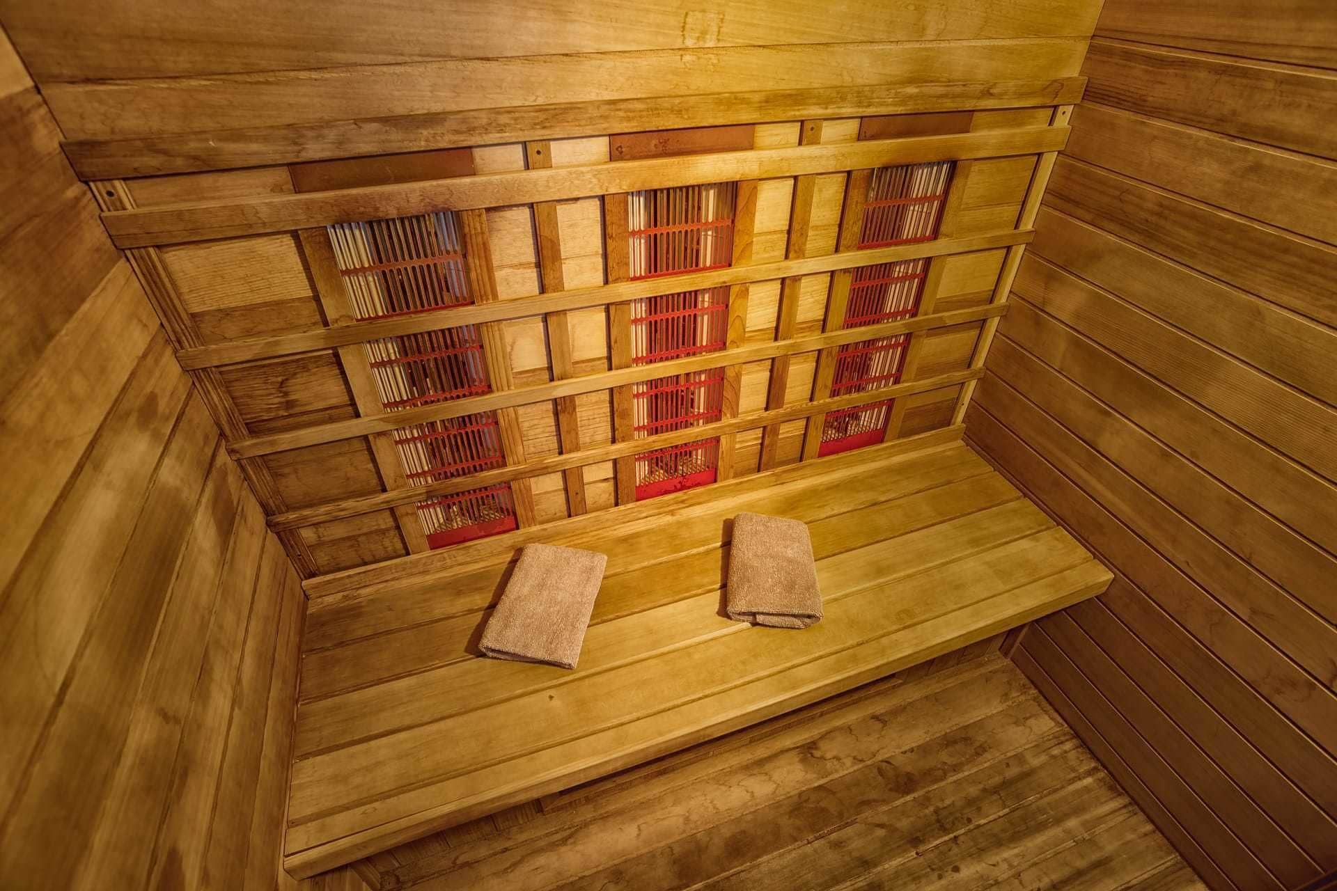 A wooden sauna with benches and red ventilation grates.