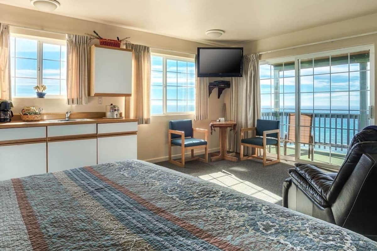 Ein Hotelzimmer mit Bett, Schreibtisch, zwei Stühlen, Fernseher und einem Balkon mit Blick.