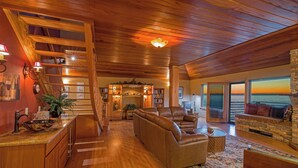 A spacious living area with a wooden ceiling, a fireplace, a sofa, and a view of the ocean. - Inn Of The Lost Coast (Shelter Cove)