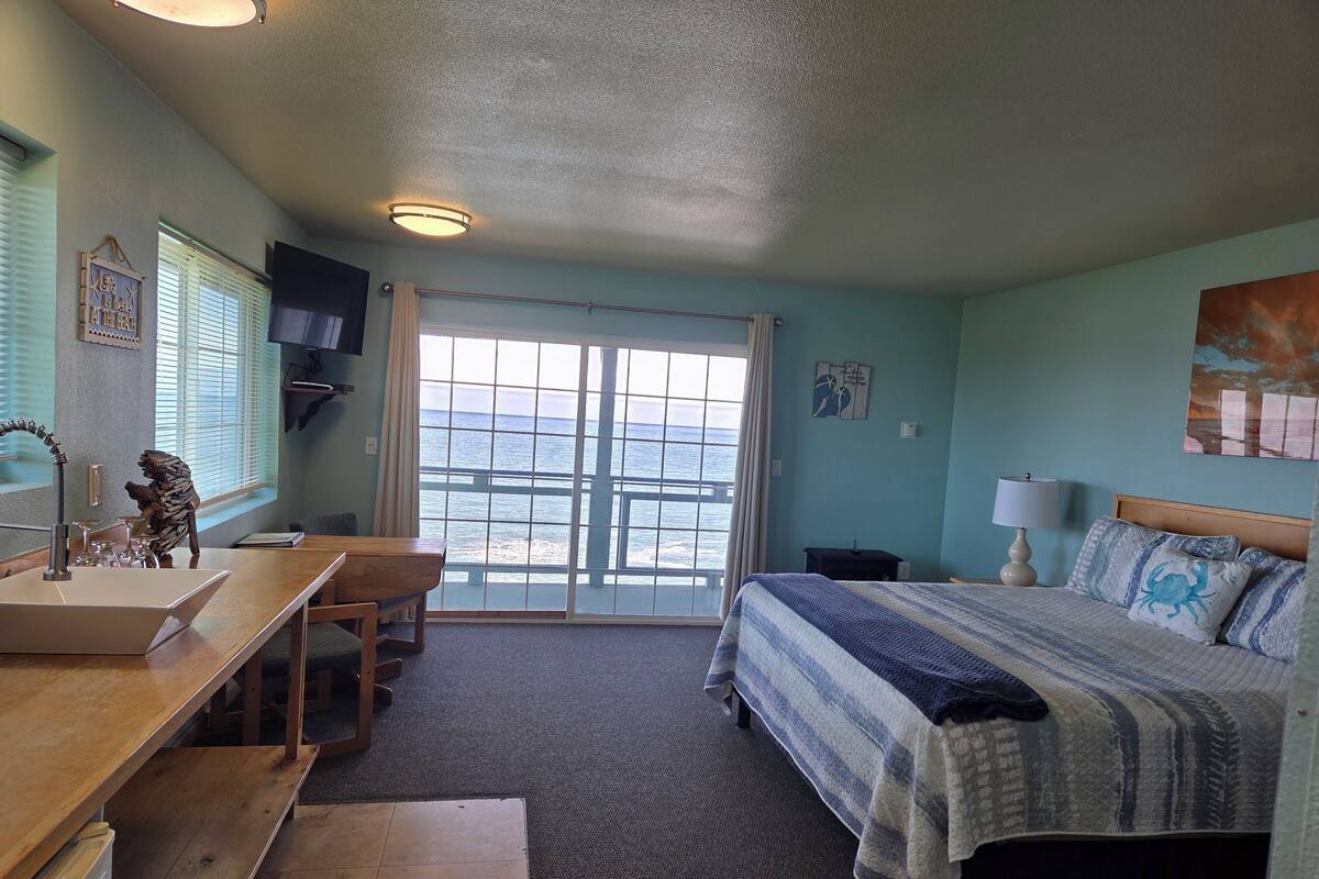 Ein Schlafzimmer mit Bett, Schreibtisch, Waschbecken und Meerblick.