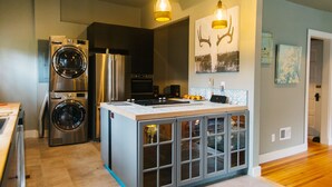 A modern kitchen with stainless steel appliances, a built-in oven, and a central island with glass-fronted cabinets. - Vintage Charm: Walk to CSU & Old Town (Fort Collins)