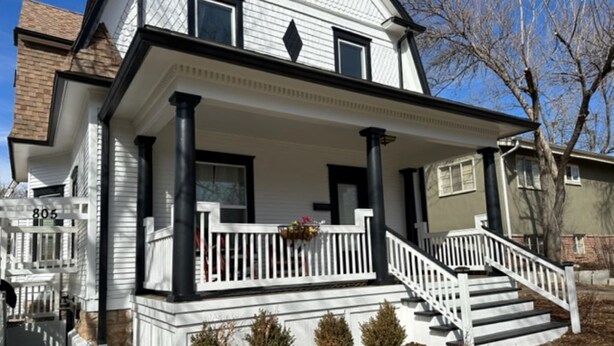 A two-story house with a front porch, white railings, and a staircase leading to the entrance. - Vintage Charm: Walk to CSU & Old Town (Fort Collins)