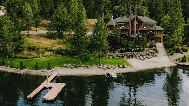 Un grand chalet doté d’un quai et d’un étang, entouré d’une forêt dense.