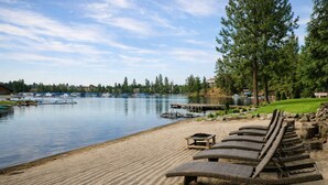 Une vue sur le lac, avec une plage de sable, des chaises longues et des bateaux amarrés.