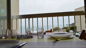 Un balcon avec une table dressée pour le dîner, offrant une vue sur la côte.