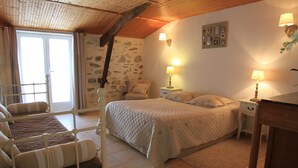 Une chambre confortable avec un lit, une chaise, une table de chevet et une lampe.