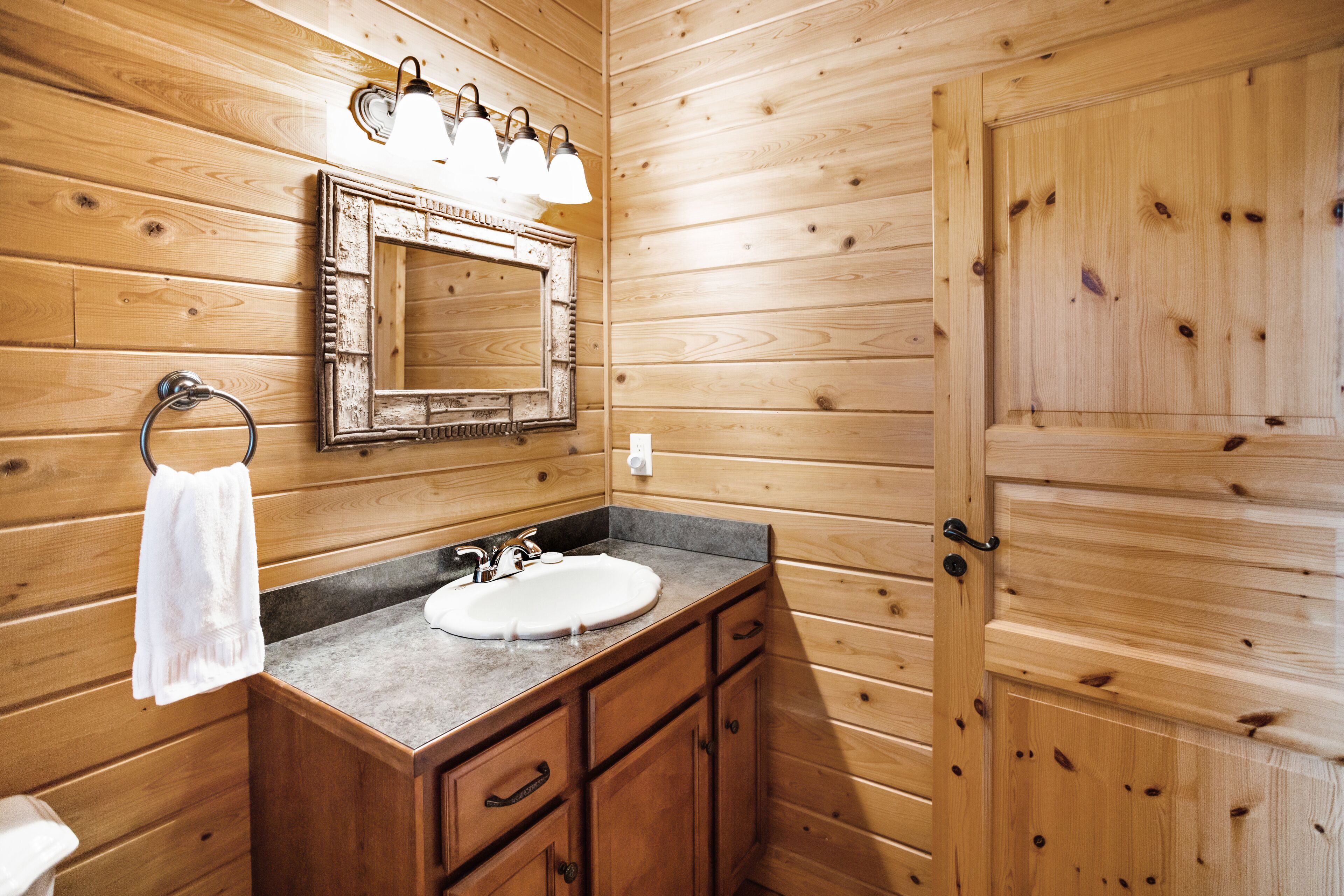 A wooden cabin-style bathroom with a sink, vanity, and a mirror.