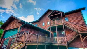 A wooden cabin with a balcony and a staircase leading to the entrance.