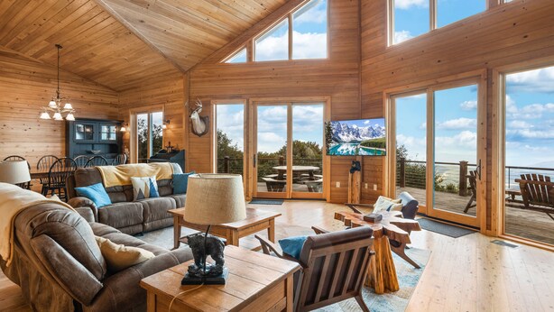 A spacious wooden cabin with a large living area, a dining table, and a view of the outdoors.