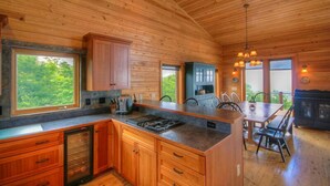 A wooden cabin interior with a kitchen island, dining table, and chairs.