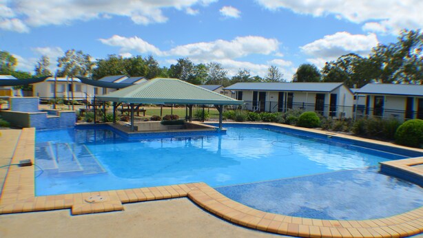 A swimming pool with a covered area, surrounded by buildings with a uniform architectural style.