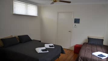 A hotel room with two beds, a ceiling fan, a door, and a small window.