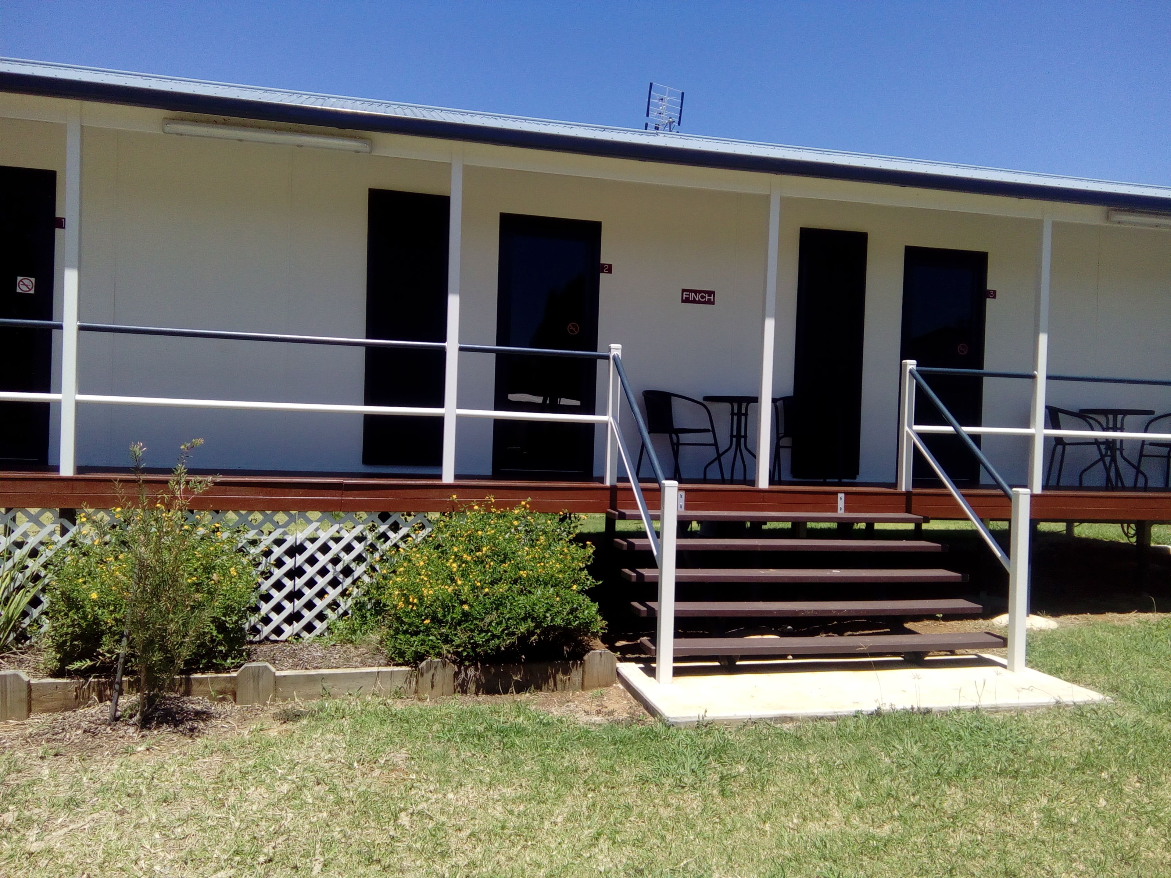 A motel with a covered porch, outdoor seating, and a sign indicating room number 2.