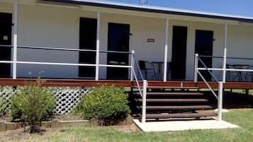 A motel with a covered porch, outdoor seating, and a sign indicating room number 2.