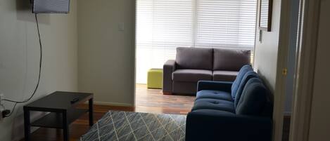 Una sala de estar con un sofá, una mesa de centro y un televisor montado en la pared.