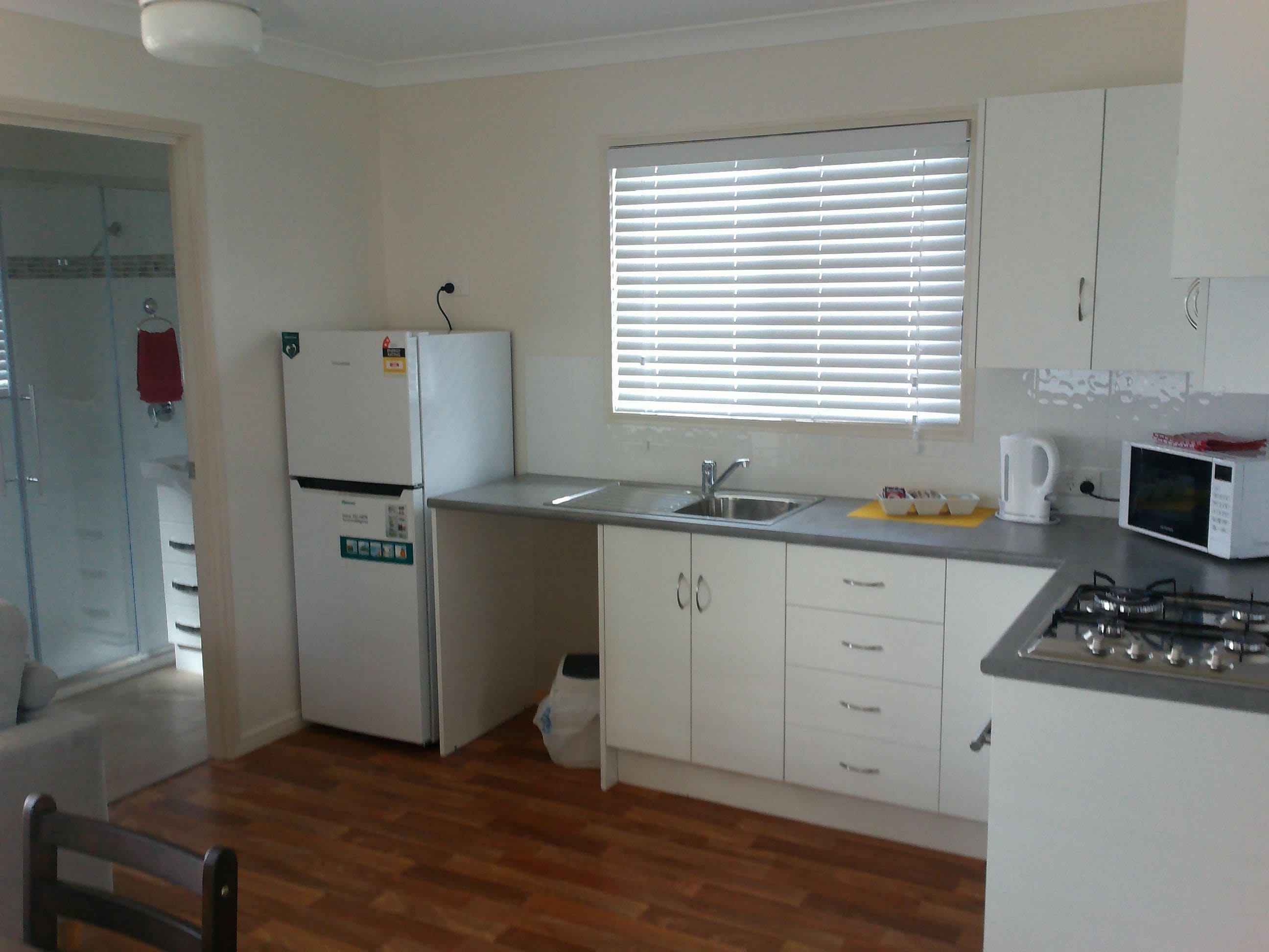 A small kitchen with a refrigerator, sink, microwave, and stove.