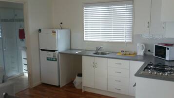 A small kitchen with a refrigerator, sink, microwave, and stove.