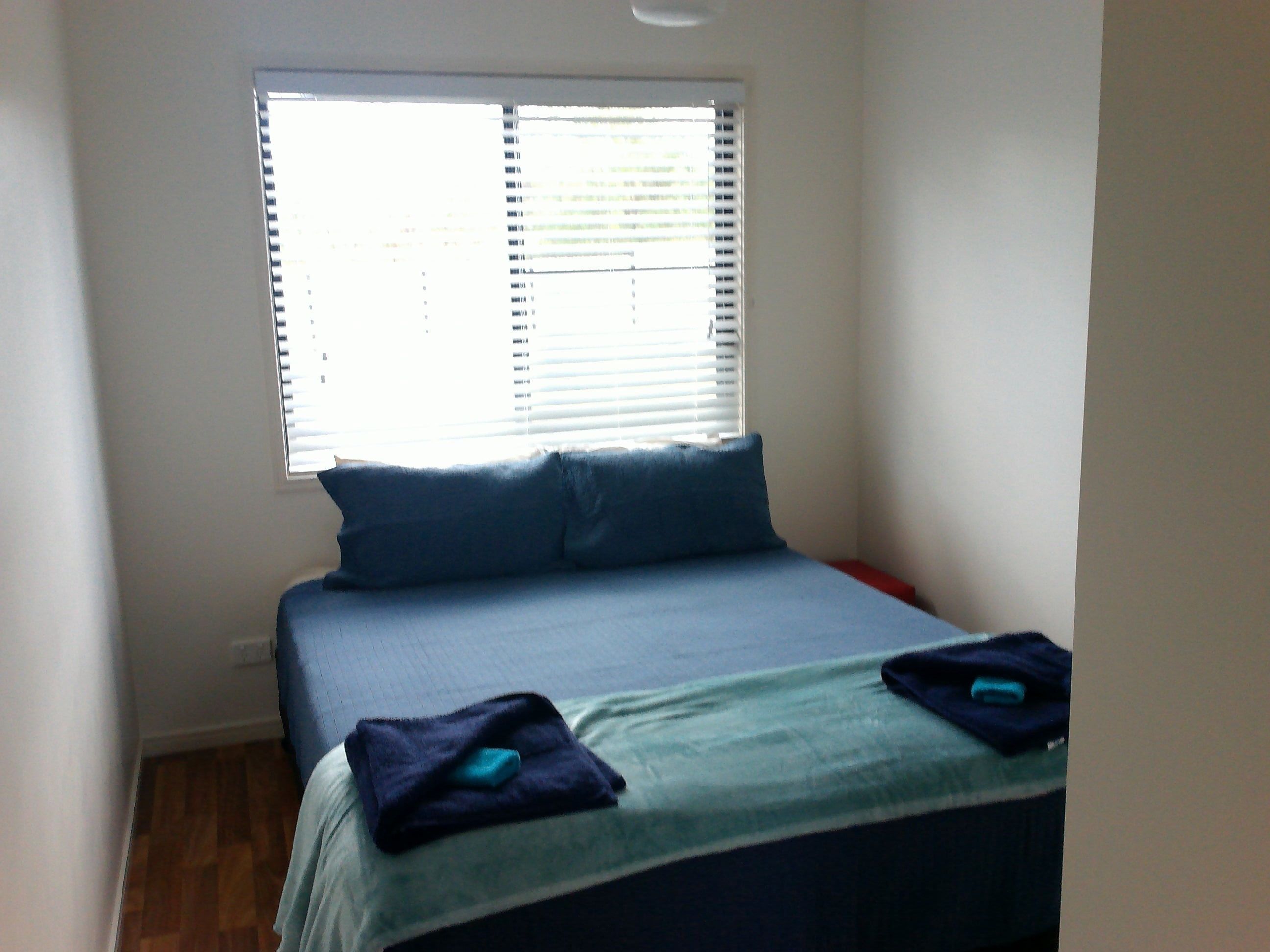 A bedroom with a bed, pillows, and a window with blinds.