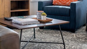 A living room with a blue armchair, a wooden cabinet, a coffee table, and a TV.