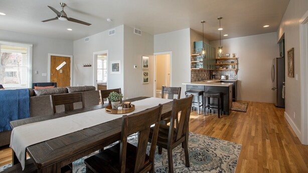 A spacious living area with a dining table, a sofa, and a kitchen area with a bar.