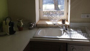 A kitchen with a window, a sink, and a dish rack. - Cottage rental Les tilleuls stone house in Perigord Noir Sarlat (Castels)