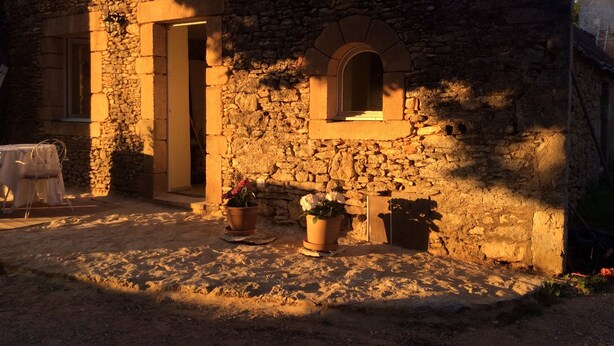 A stone building with a small arched window and a door, surrounded by potted plants. - Cottage rental Les tilleuls stone house in Perigord Noir Sarlat (Castels)