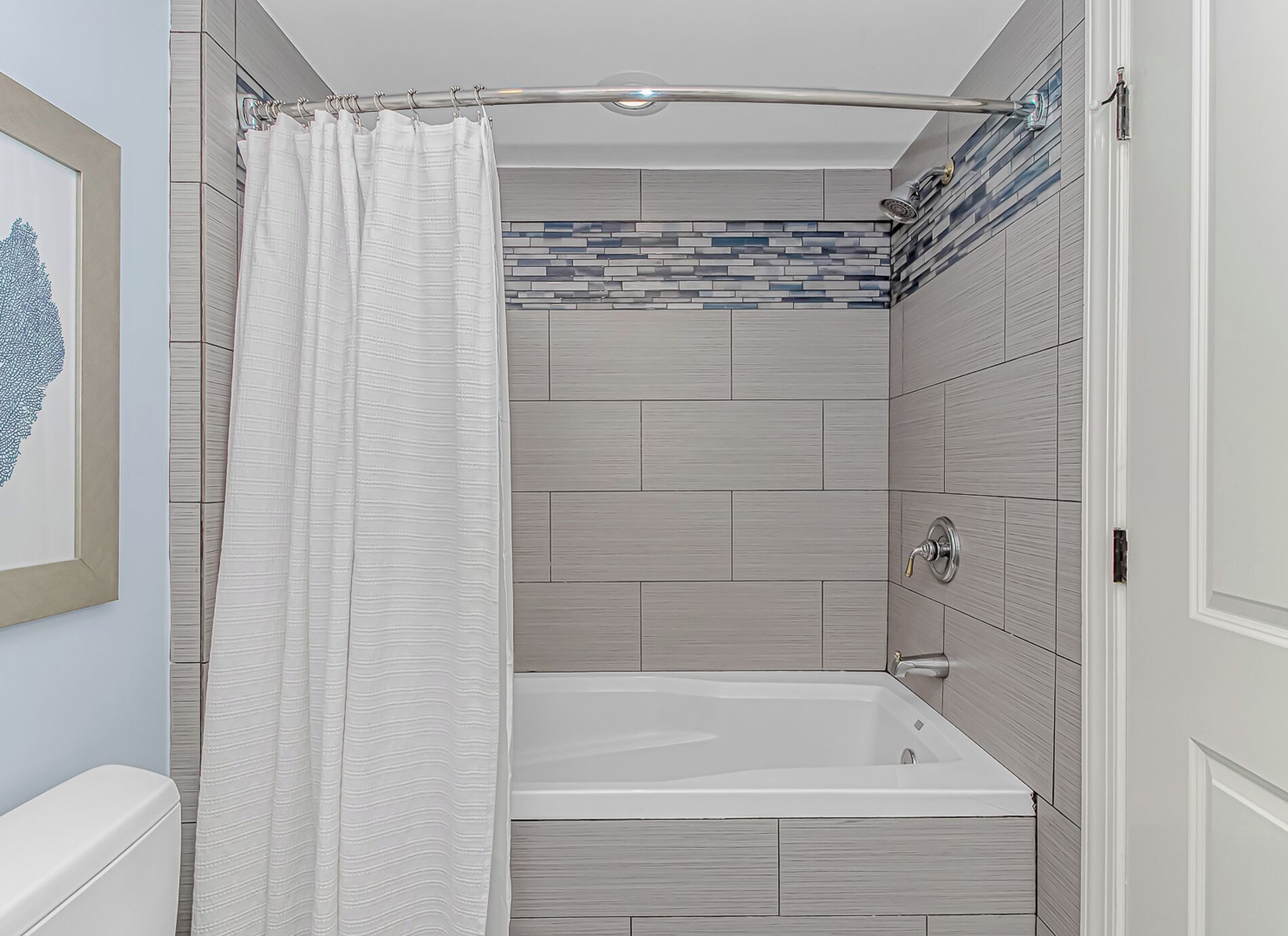 Une salle de bain avec un rideau de douche, une baignoire et des murs carrelés.