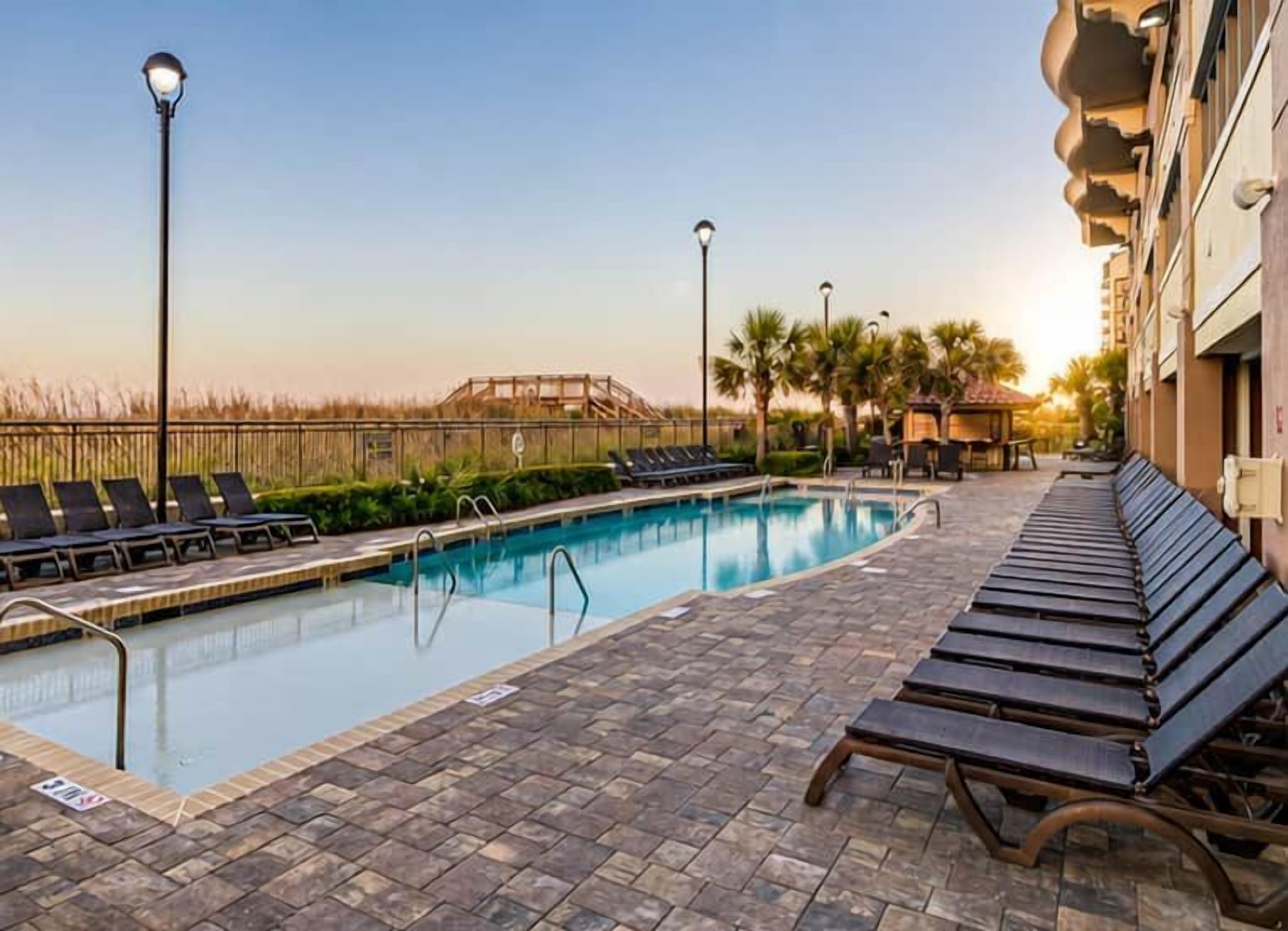 A swimming pool with lounge chairs and a building with balconies.