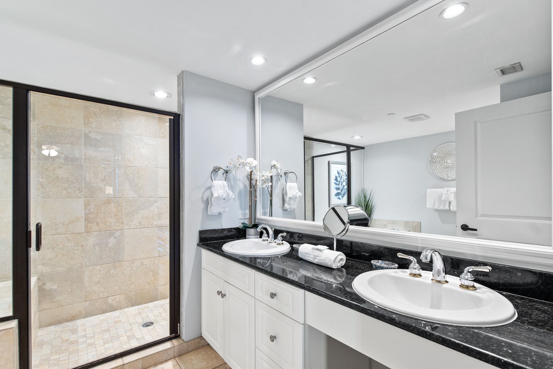 Un baño moderno con dos lavamanos, un espejo grande y una cabina de ducha de vidrio.
